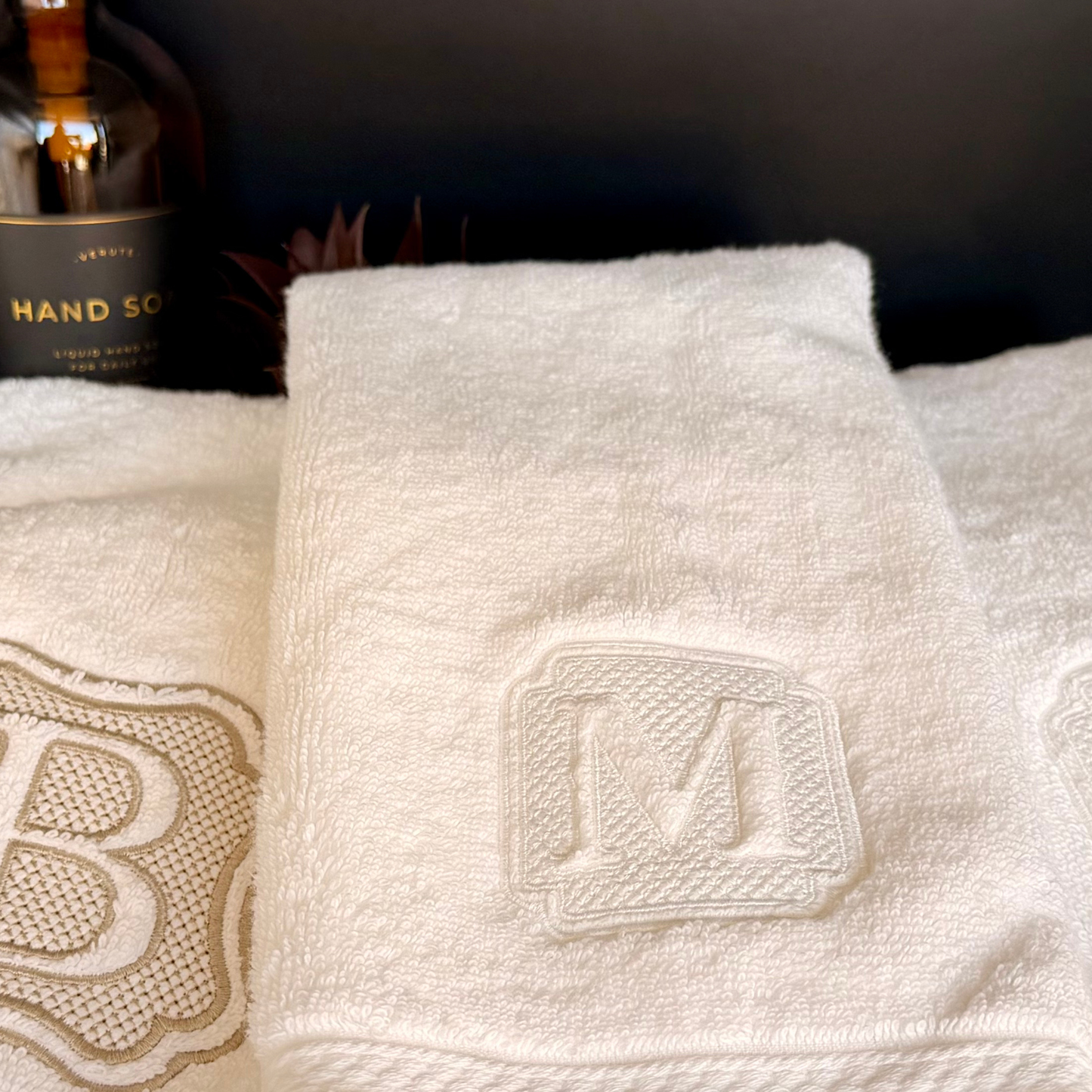 White luxury hand towels with custom embroidered monograms with hand soap.
